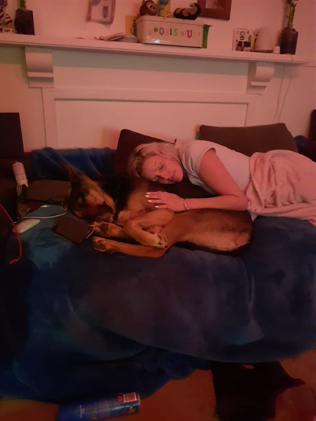 Bianca and a tan and black dog snuggled up asleep on a couch